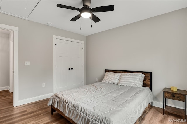 bedroom featuring a closet, baseboards, ceiling fan, and wood finished floors