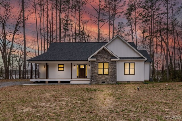 view of front facade featuring a porch, stone siding, crawl space, a front lawn, and roof with shingles