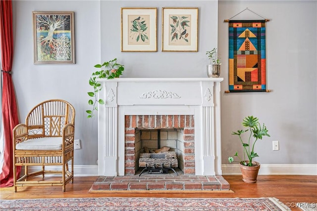 living area featuring baseboards, wood finished floors, and a fireplace
