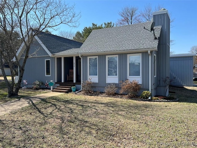 view of front of house featuring a front lawn, roof with shingles, and a chimney