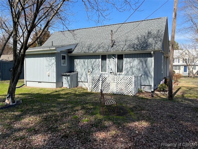back of house featuring crawl space, a lawn, and a shingled roof