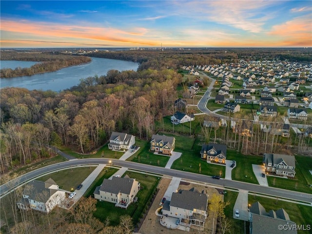 aerial view at dusk with a wooded view, a residential view, and a water view