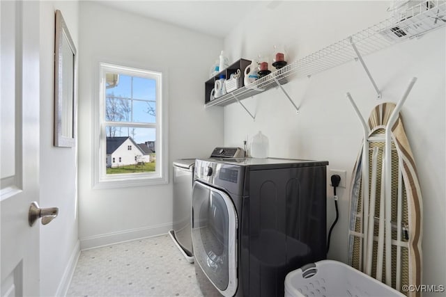 laundry room with washer and clothes dryer, light floors, laundry area, and baseboards