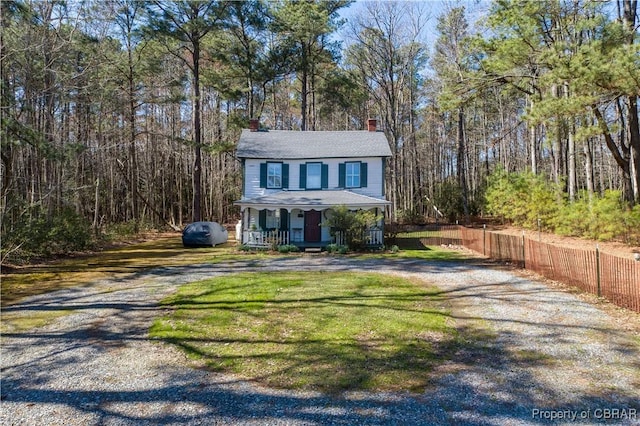 257 Horseshoe Bend Rd, Deltaville, VA 23043 - view of front of house featuring a chimney, covered porch, gravel driveway, and a forest view