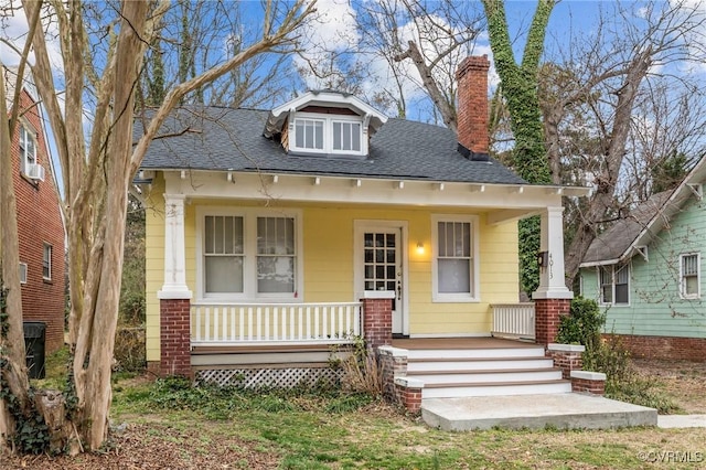 view of front of home with a porch, a chimney, and roof with shingles