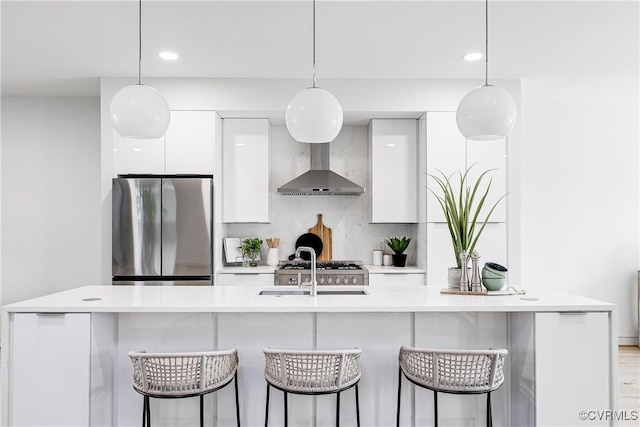 kitchen with freestanding refrigerator, modern cabinets, wall chimney range hood, white cabinets, and light countertops