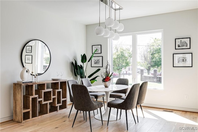 dining room featuring wood finished floors, visible vents, and a healthy amount of sunlight