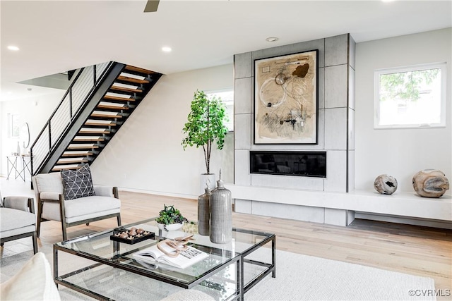 living area featuring recessed lighting, stairs, a fireplace, and wood finished floors