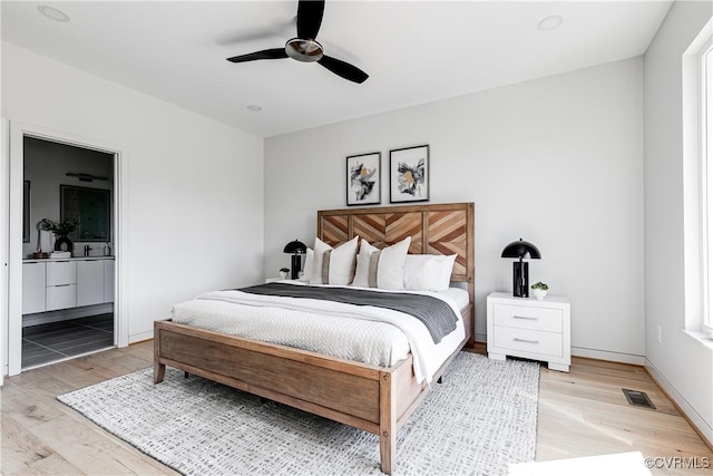 bedroom featuring light wood-type flooring, a ceiling fan, visible vents, and connected bathroom