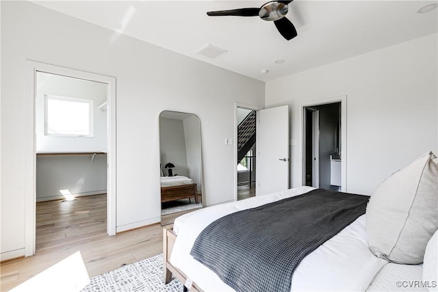 bedroom with light wood-type flooring, baseboards, visible vents, ceiling fan, and arched walkways