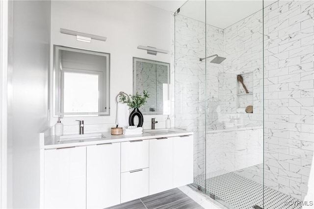 full bath featuring a sink, a shower stall, and double vanity