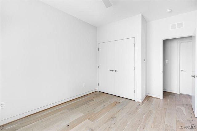 unfurnished bedroom with ceiling fan, visible vents, a closet, and wood finished floors