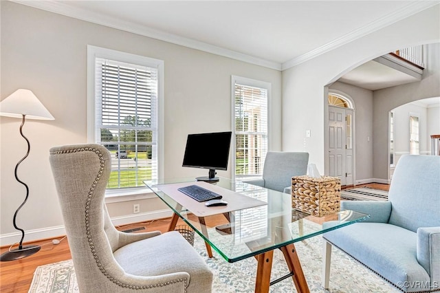 office with arched walkways, baseboards, ornamental molding, and wood finished floors