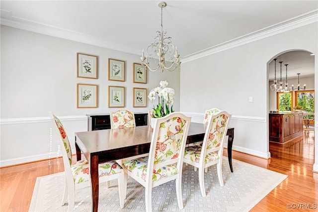 dining room with arched walkways, a notable chandelier, crown molding, and light wood-style floors