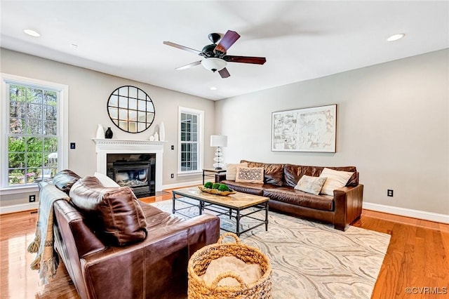 living room featuring a ceiling fan, recessed lighting, baseboards, a fireplace with flush hearth, and wood finished floors