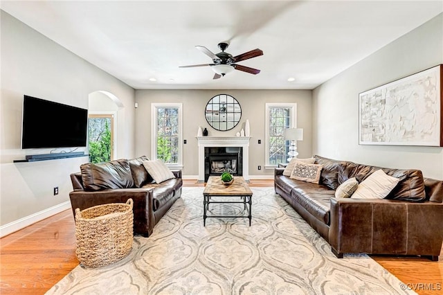living room with wood finished floors, baseboards, ceiling fan, and arched walkways