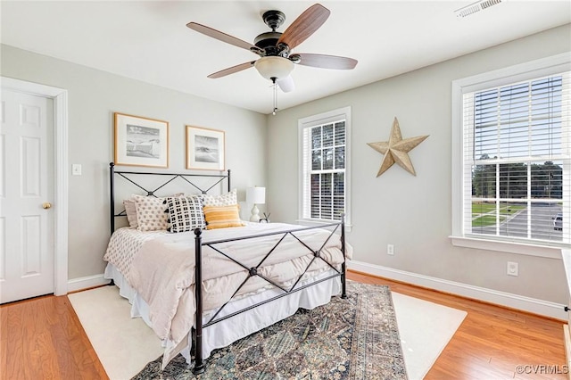 bedroom with ceiling fan, light wood-style flooring, baseboards, and visible vents