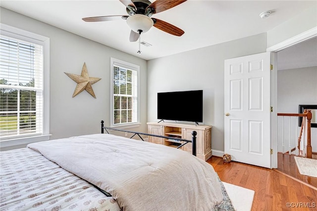 bedroom with baseboards, visible vents, light wood-style flooring, and a ceiling fan