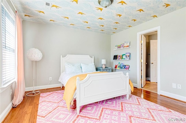 bedroom featuring baseboards, visible vents, and wood finished floors