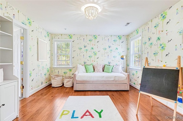 bedroom featuring visible vents, light wood-type flooring, wallpapered walls, and multiple windows