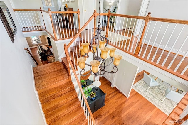 stairway featuring a notable chandelier and wood finished floors