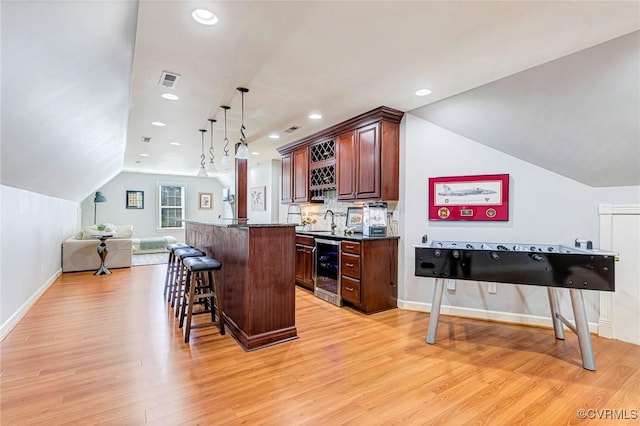 kitchen with wine cooler, lofted ceiling, open floor plan, a kitchen breakfast bar, and dark countertops