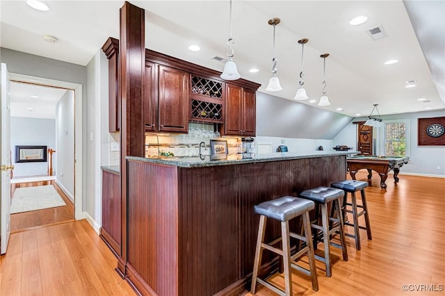bar featuring light wood-style floors, visible vents, indoor wet bar, and tasteful backsplash