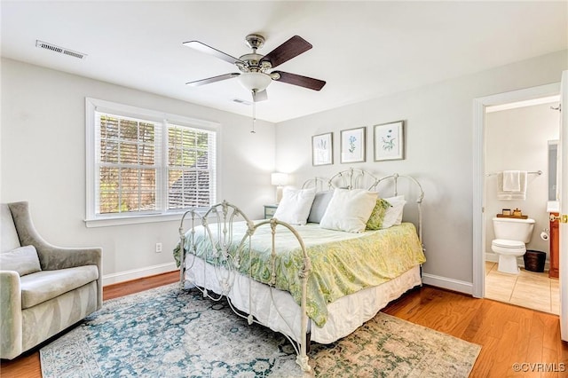 bedroom with baseboards, visible vents, and wood finished floors