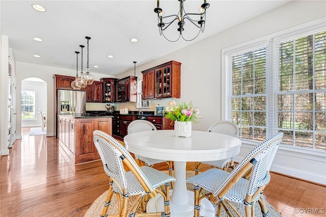 dining room with recessed lighting, a chandelier, light wood-style flooring, arched walkways, and baseboards