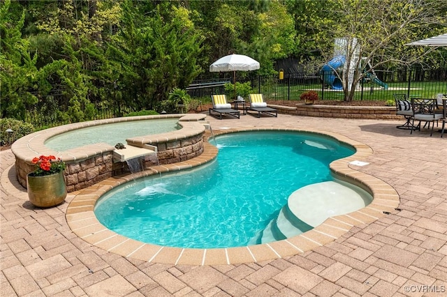 view of pool with a pool with connected hot tub, a playground, fence, and a patio