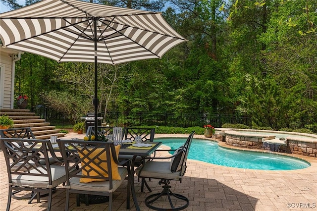 view of swimming pool featuring a patio, an in ground hot tub, fence, outdoor dining area, and a fenced in pool
