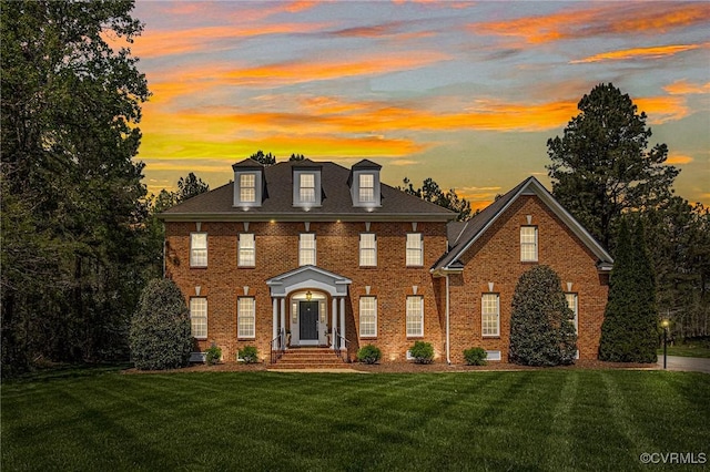 colonial house featuring brick siding and a front yard