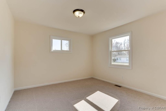 carpeted spare room featuring visible vents and baseboards
