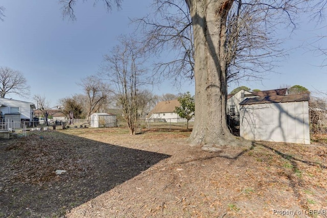 view of yard featuring an outdoor structure, a storage unit, and fence