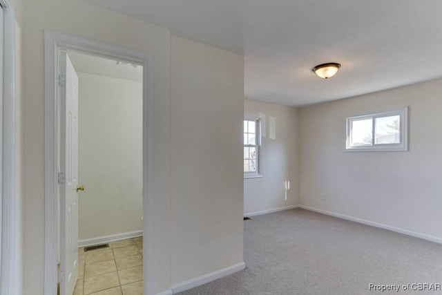 spare room featuring visible vents, baseboards, light carpet, and light tile patterned flooring