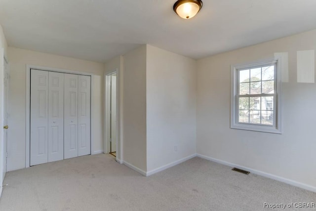 unfurnished bedroom with visible vents, carpet floors, baseboards, and a closet