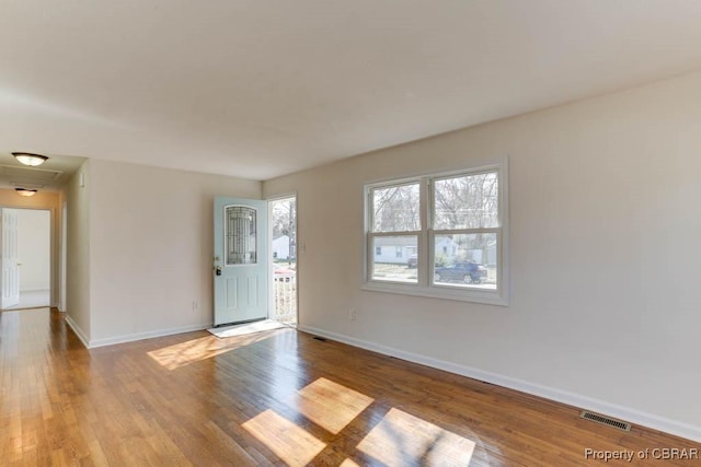 spare room with visible vents, baseboards, and wood finished floors