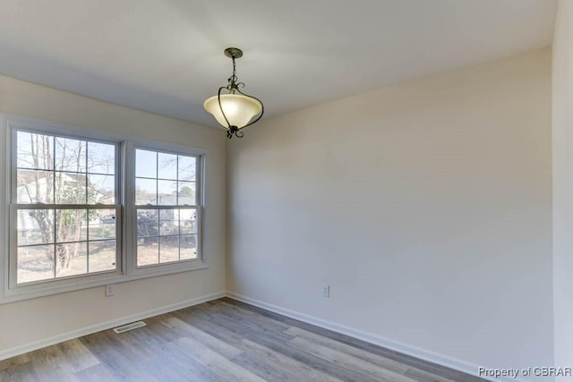 spare room with visible vents, baseboards, and wood finished floors