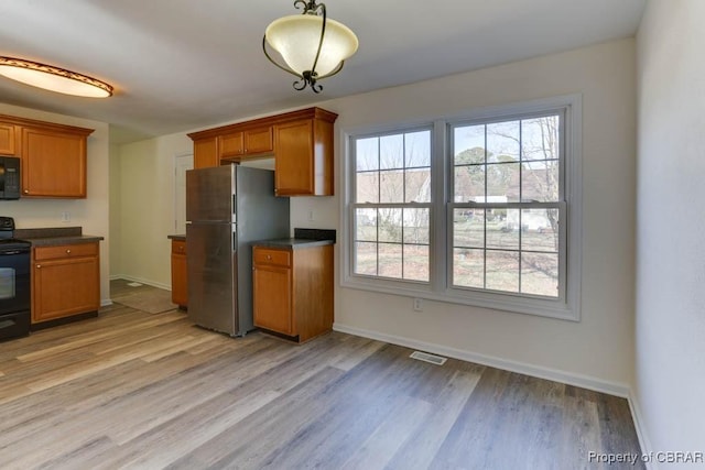 kitchen with black appliances, brown cabinetry, and dark countertops