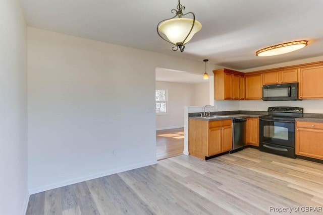 kitchen featuring dark countertops, black appliances, light wood-style flooring, and hanging light fixtures