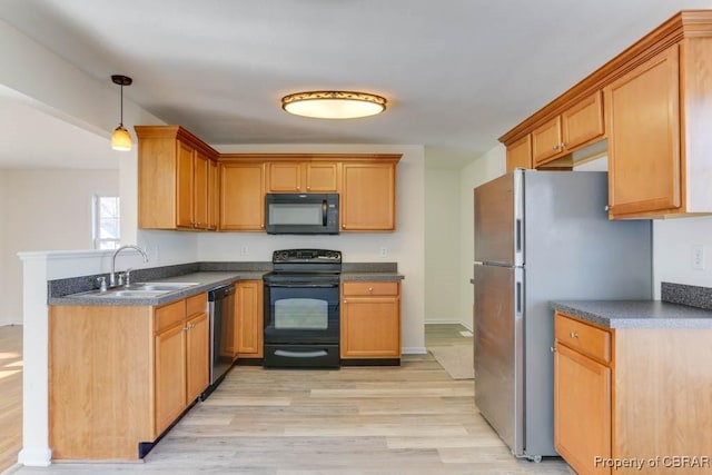kitchen featuring dark countertops, light wood-style flooring, black appliances, and a sink