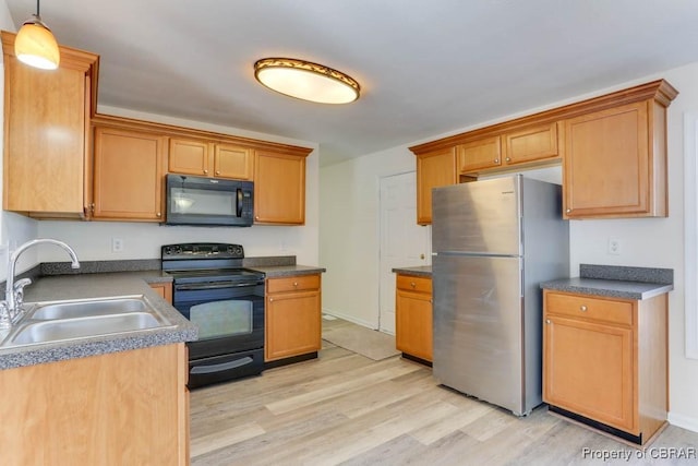 kitchen with dark countertops, light wood-style flooring, black appliances, and a sink