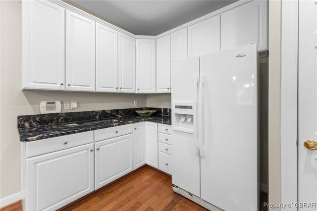 22 Crossroad, Irvington, VA 22480 - kitchen with wood finished floors, baseboards, dark stone counters, white cabinets, and white fridge with ice dispenser