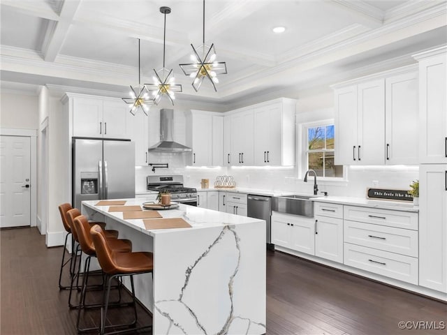 kitchen featuring an inviting chandelier, wall chimney exhaust hood, a sink, appliances with stainless steel finishes, and white cabinetry