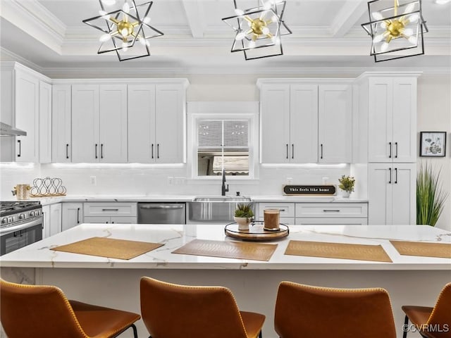 kitchen with a notable chandelier, white cabinets, a kitchen bar, appliances with stainless steel finishes, and a sink