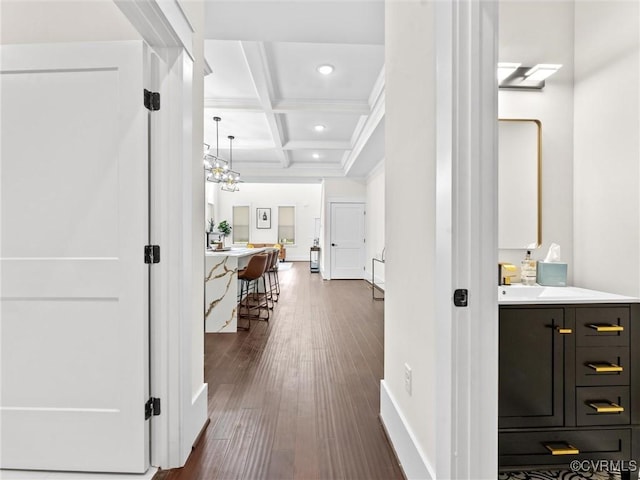 corridor with baseboards, coffered ceiling, recessed lighting, beamed ceiling, and dark wood finished floors