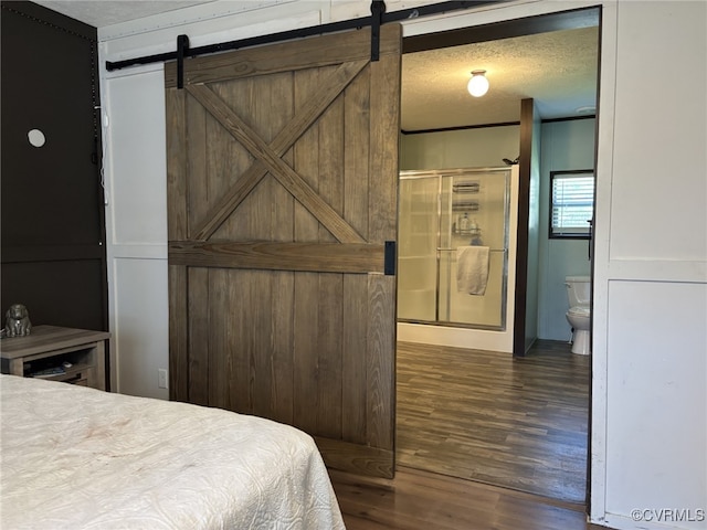 16690 Shands Rd, South Prince George, VA 23805 - bedroom featuring a barn door, dark wood-type flooring, a textured ceiling, and ensuite bath