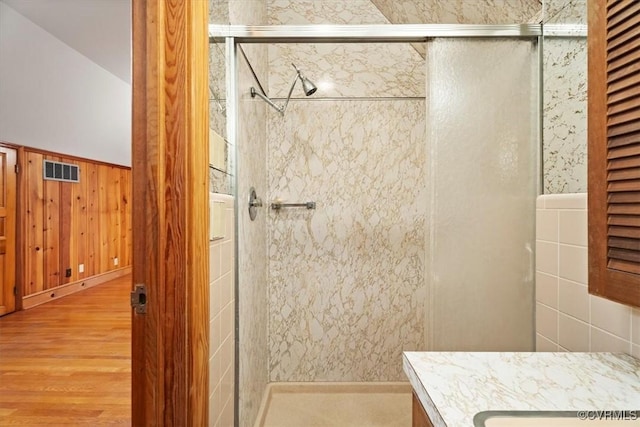 bathroom featuring a shower stall, a wainscoted wall, wood finished floors, visible vents, and vanity