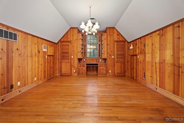 bonus room featuring a chandelier, wooden walls, vaulted ceiling, and light wood finished floors