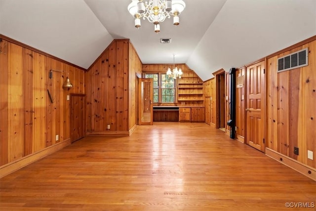 additional living space with light wood-style flooring, visible vents, a notable chandelier, and vaulted ceiling